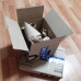 Раскрытая коробка с товаром из интернет-магазина озон стоит на другой коробке упакованной и перевязанной скотчем с логотипом ozon.